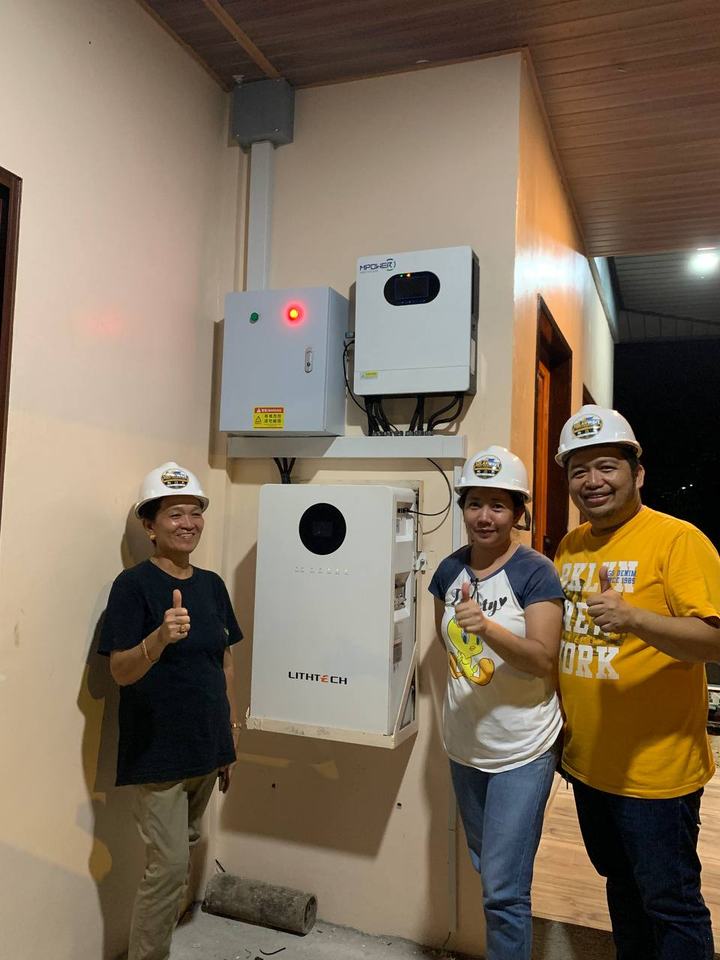 Three SolarWave team members in hard hats beside a newly installed inverter and battery